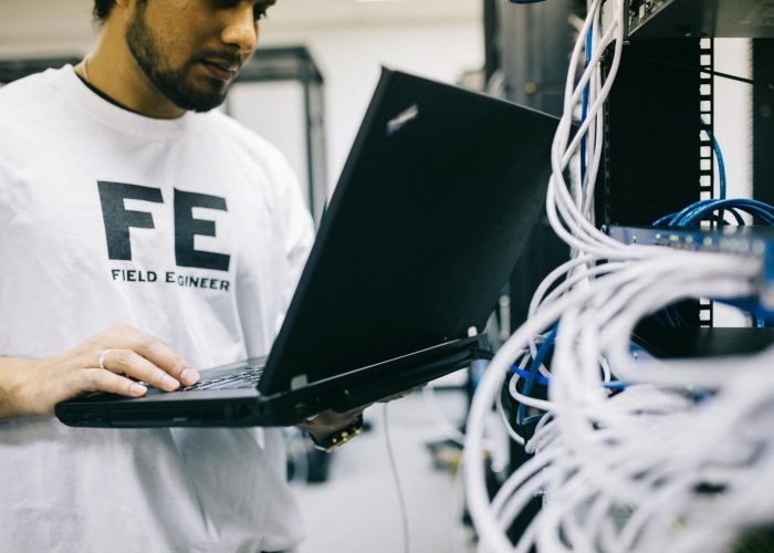 Crop focused Asian engineer in white shirt using modern netbook while working with hardware